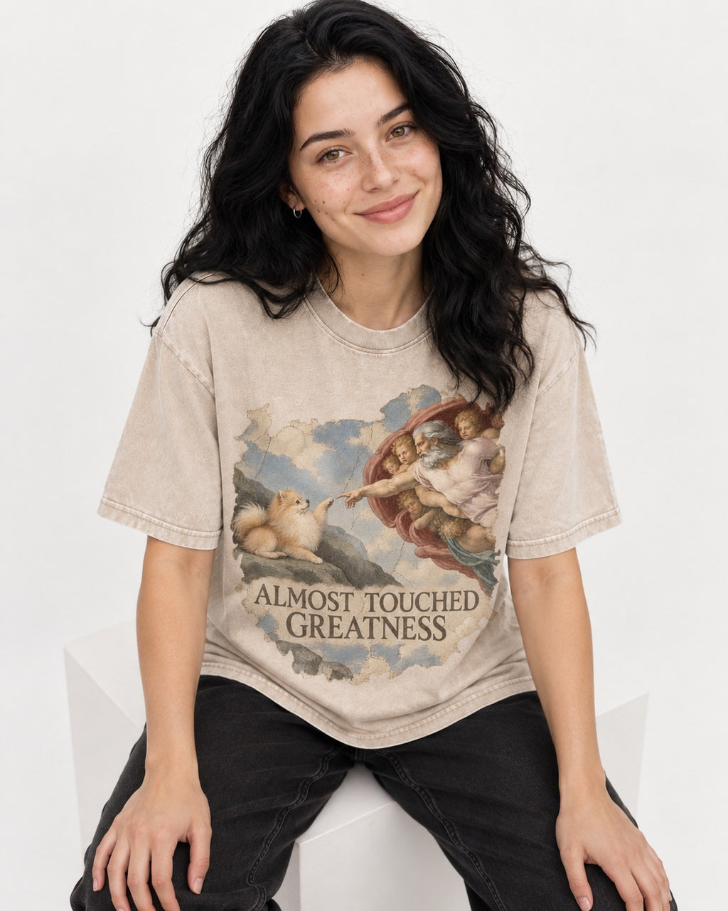 Pomeranian Almost Touched Greatness Fresco Graphic Washed Tee in Apricot, worn by a seated model