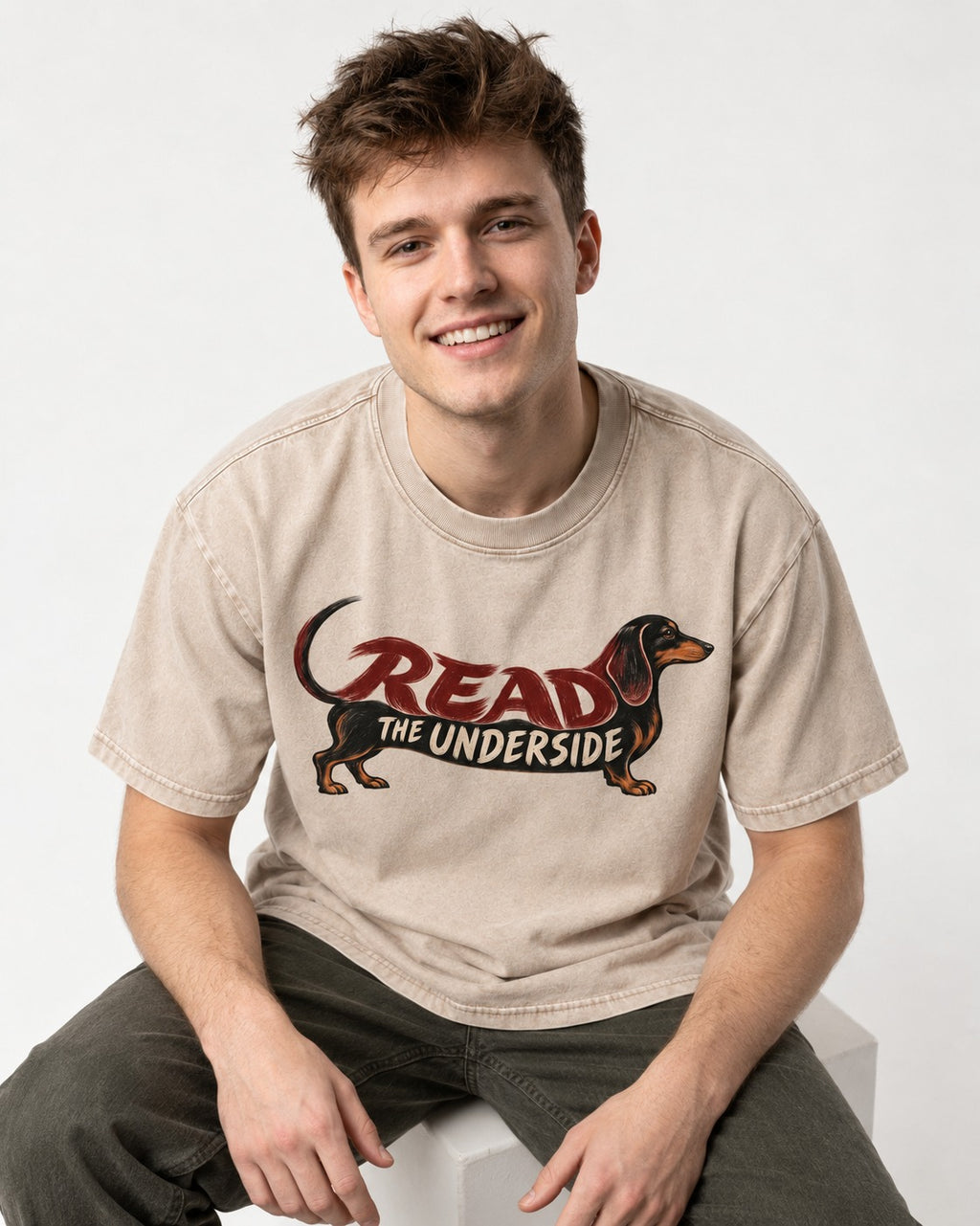 Dachshund Read The Underside Body Lettering Graphic Washed Tee in Apricot, worn by a seated model