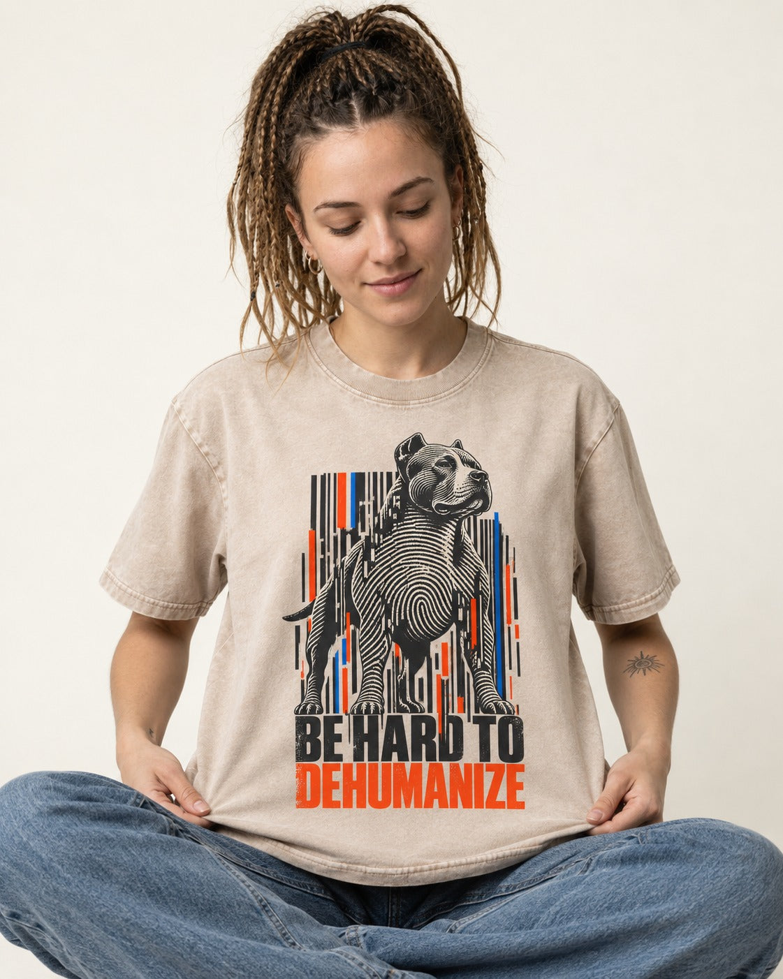 Pitbull Hard to Dehumanize Washed Tee in Apricot, worn by a seated model