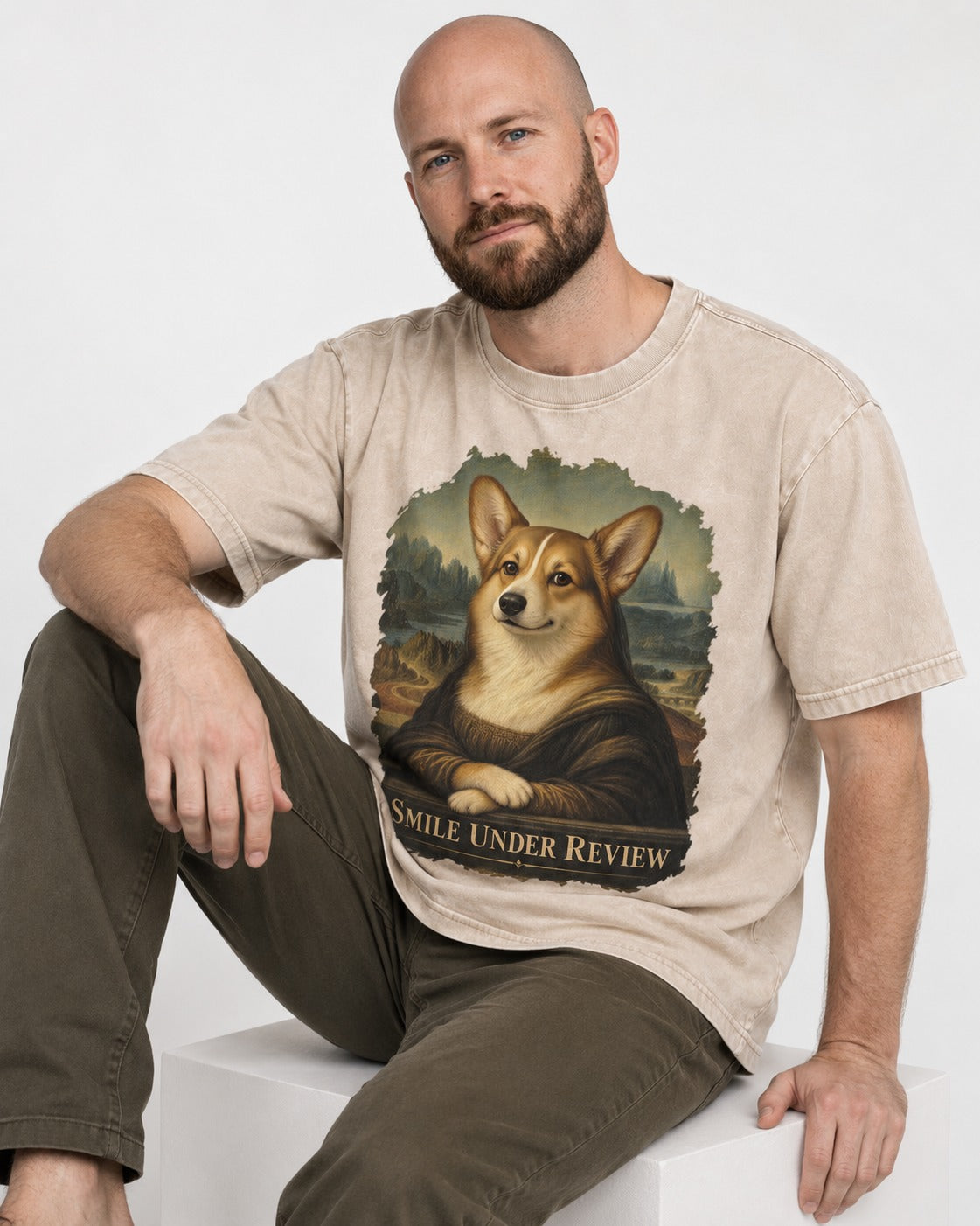 Corgi Smile Under Review Mona Lisa Portrait Washed Tee in Apricot, worn by a seated model