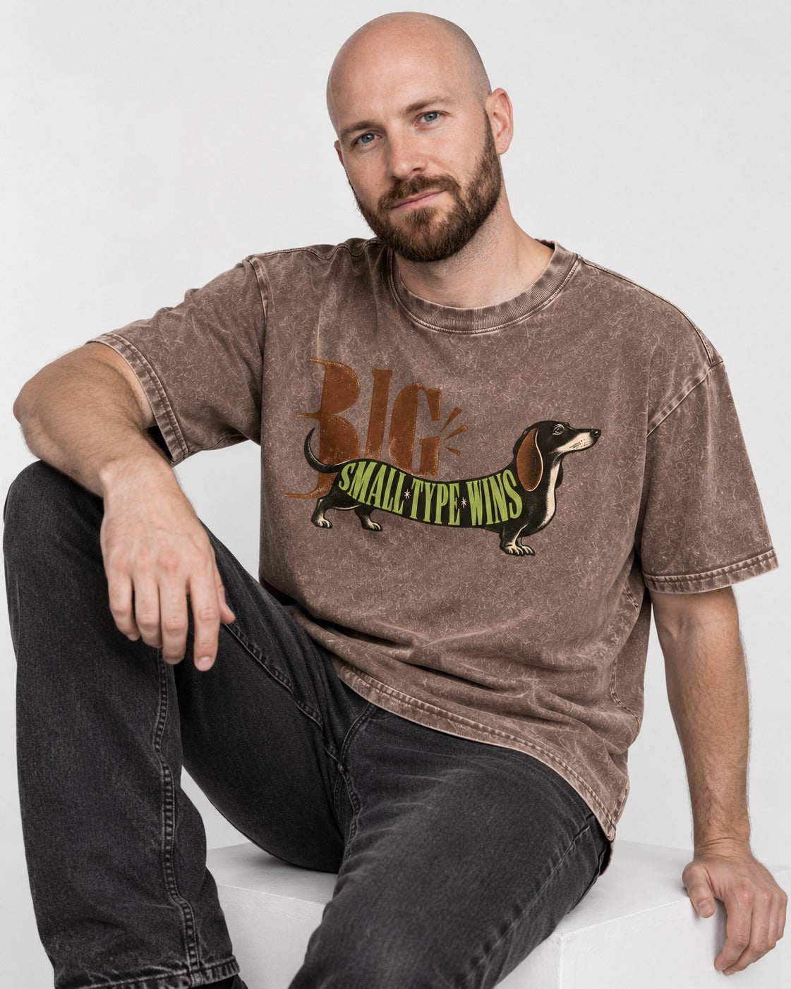Dachshund Small Type Wins Washed Tee in Coffee, worn by a seated model