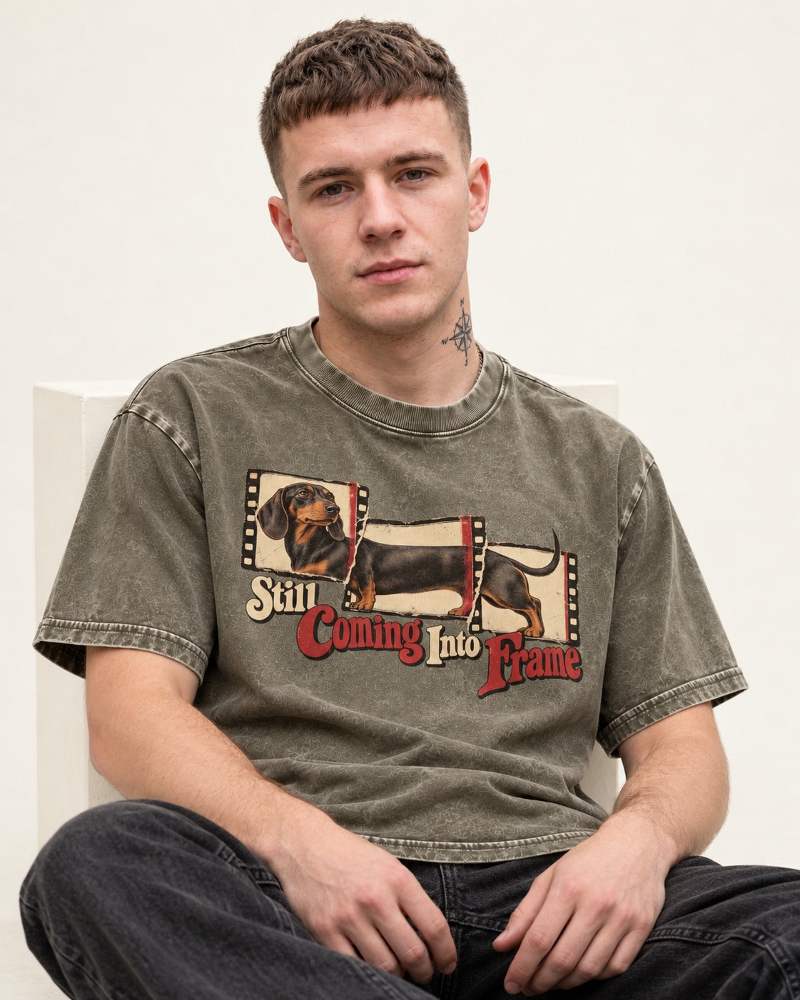 Dachshund Still Coming Into Frame Vintage Filmstrip Graphic Washed Tee in Army Green, worn by a seated model