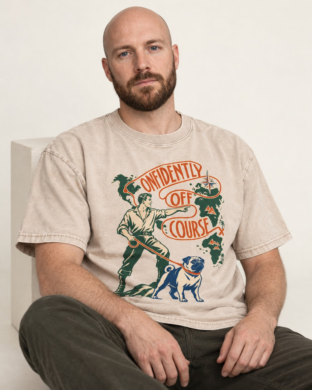 Pug Confidently Off Course Washed Tee in Apricot, worn by a seated model
