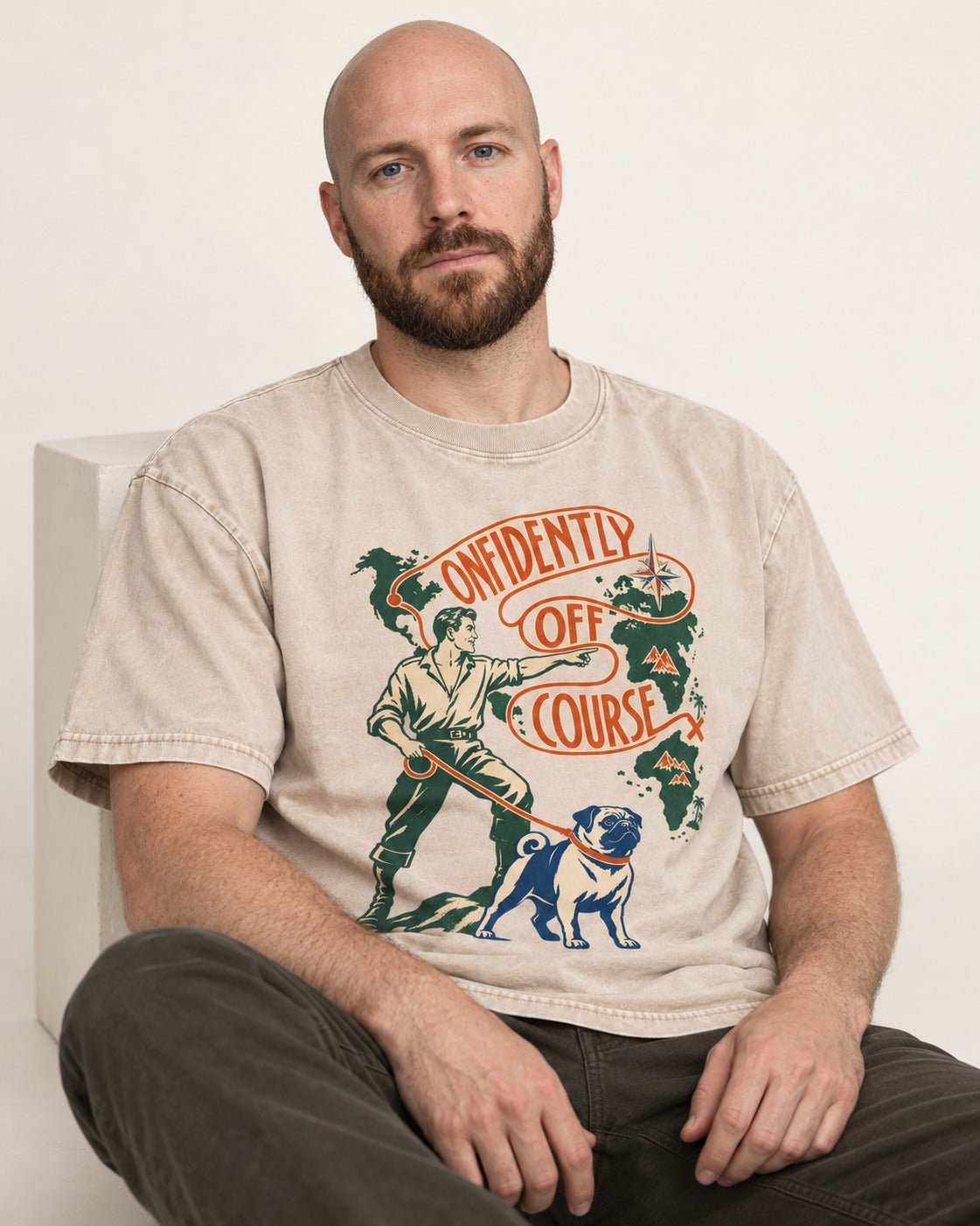 Pug Confidently Off Course Washed Tee in Apricot, worn by a seated model