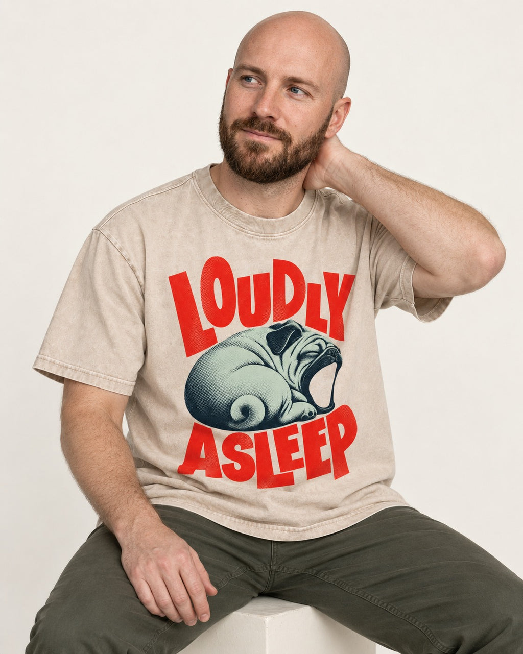 Pug Loudly Asleep Curled Yawn Graphic Washed Tee in Apricot, worn by a seated model
