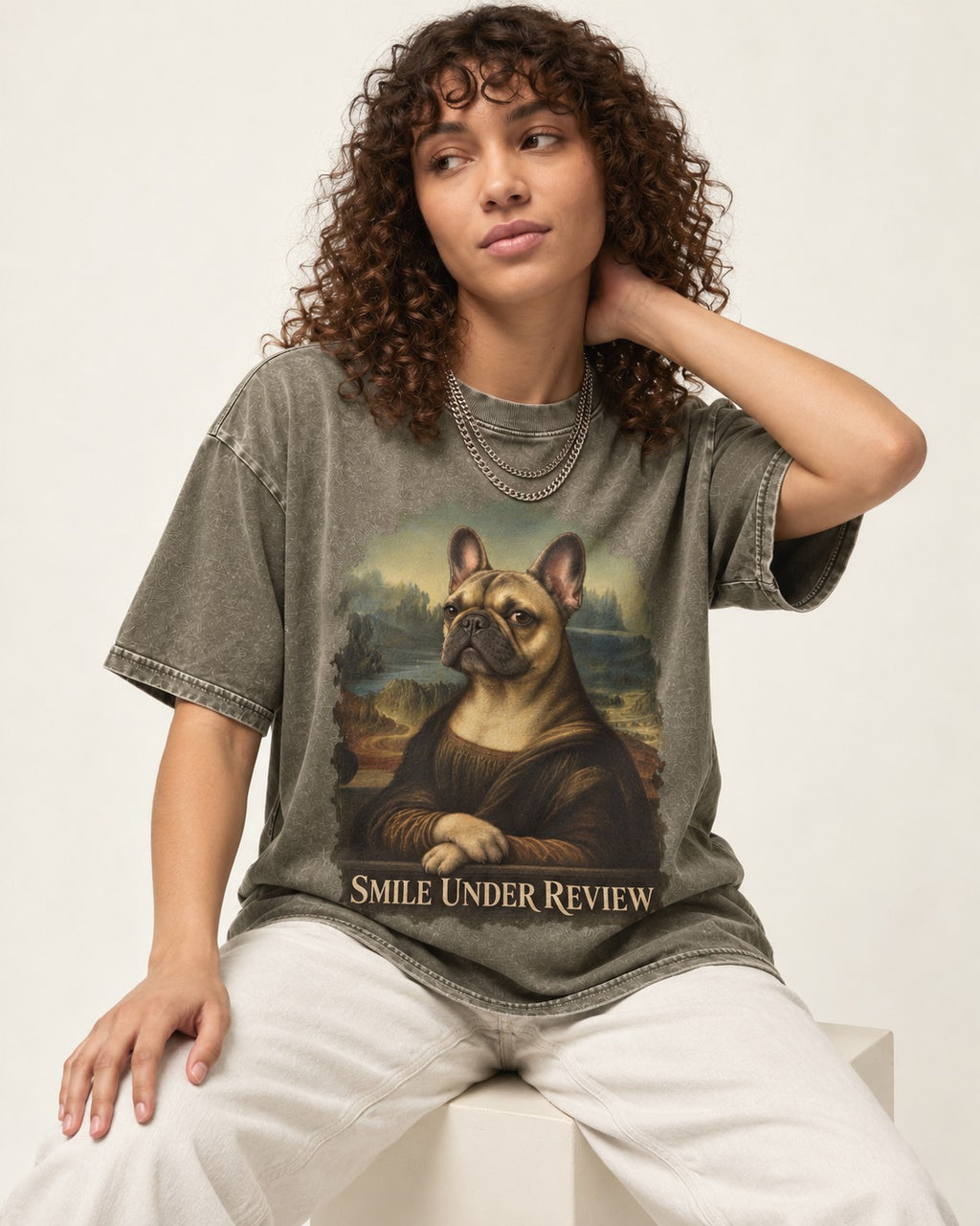Frenchie Smile Under Review Renaissance Portrait Washed Tee in Army Green, worn by a seated model