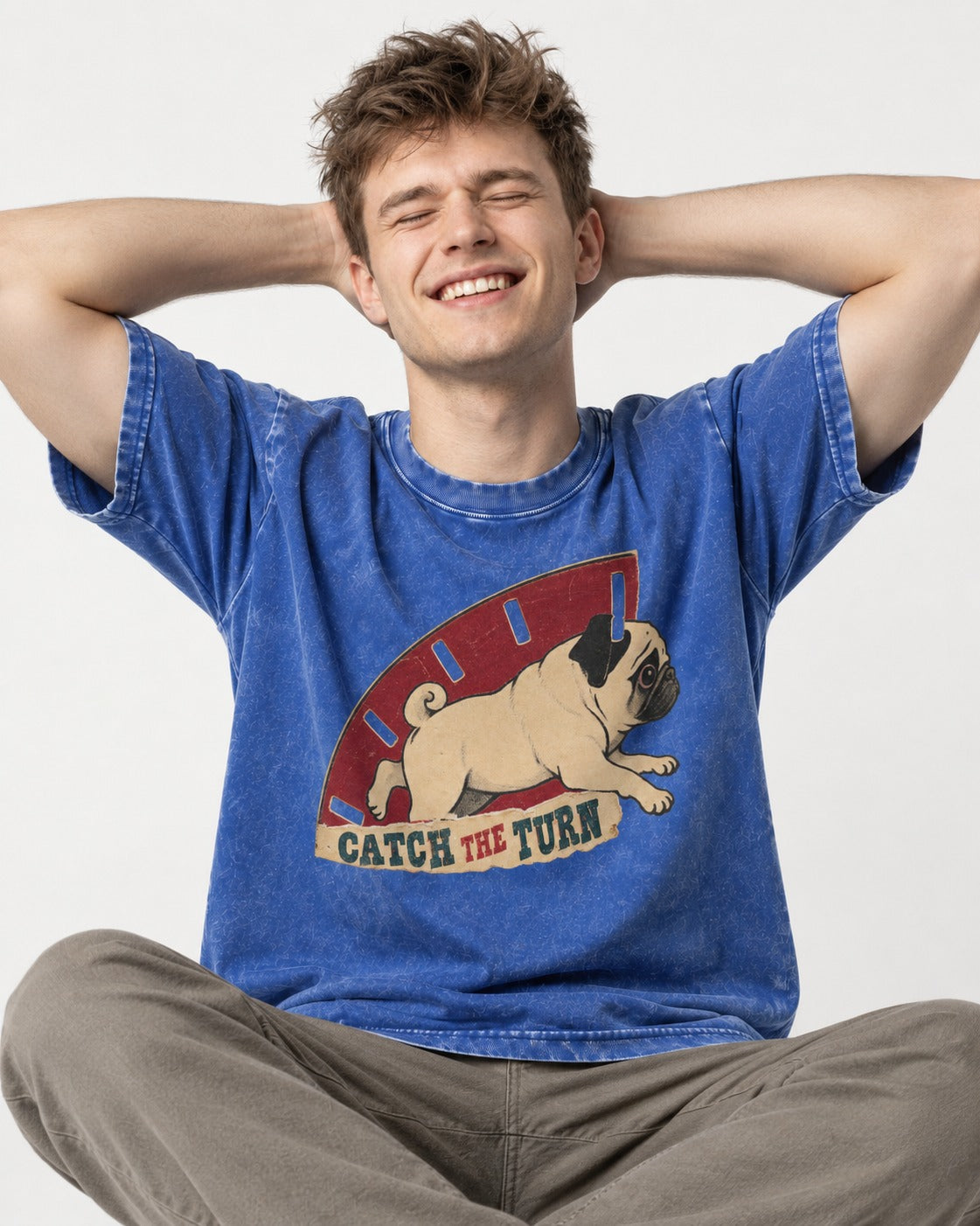 Pug Catch the Turn Track Graphic Washed Tee in Royal Blue, worn by a seated model