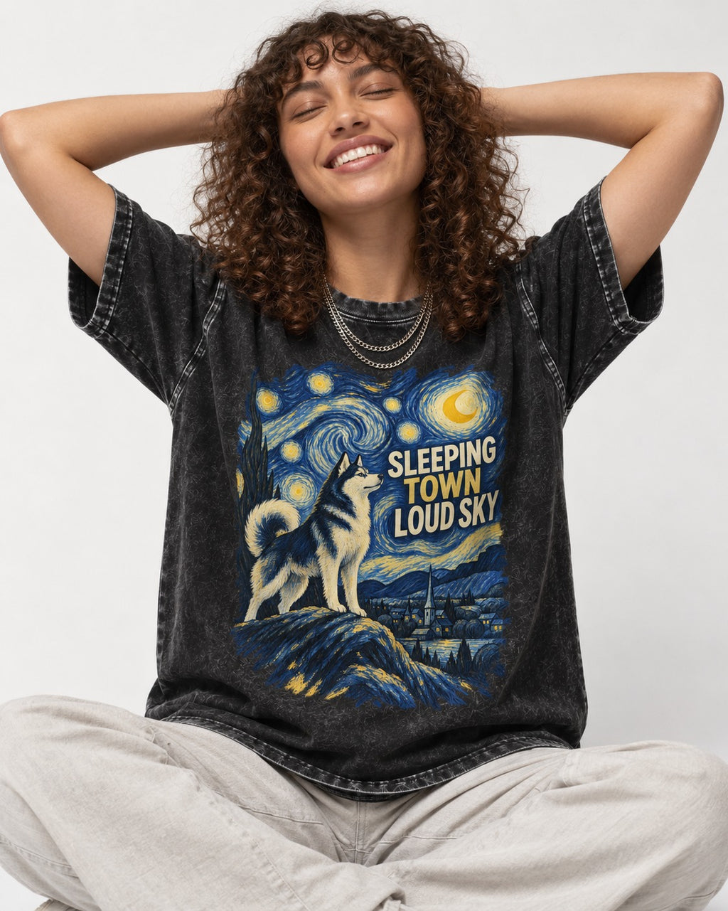 Husky Sleeping Town Loud Sky Starry Night Graphic Washed Tee in Black, worn by a seated model