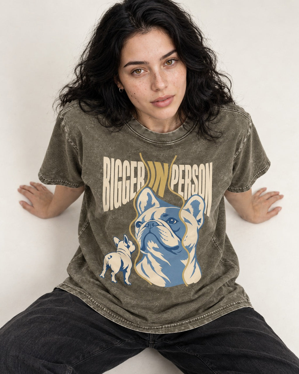 Frenchie Bigger in Person Mirror Graphic Washed Tee in Army Green, worn by a seated model