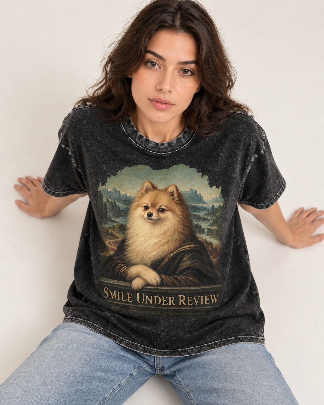 Pomeranian Smile Under Review Renaissance Portrait Graphic Washed Tee in Black, worn by a seated model