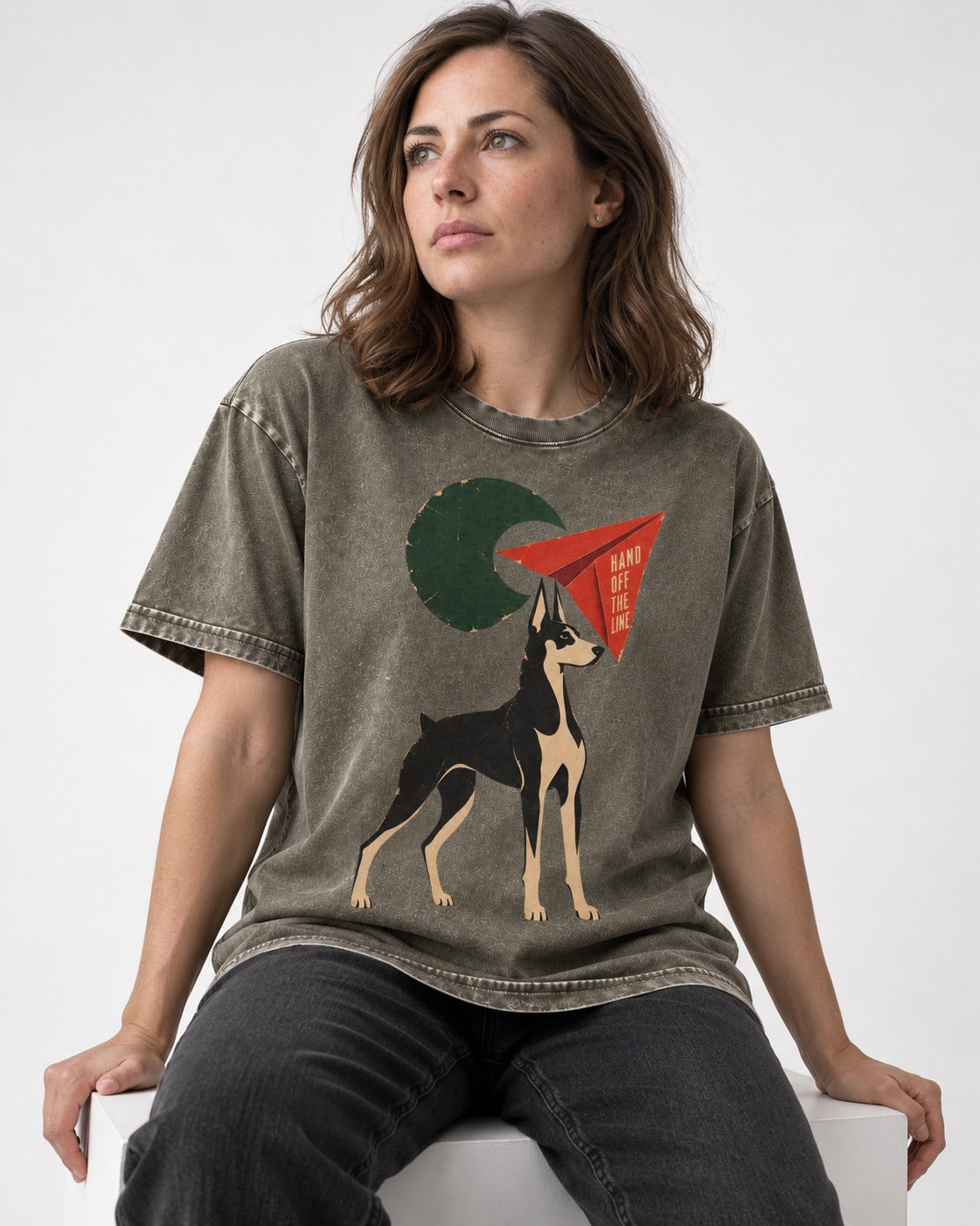 Doberman Hand Off the Line Paper Plane Graphic Washed Tee in Army Green, worn by a seated model