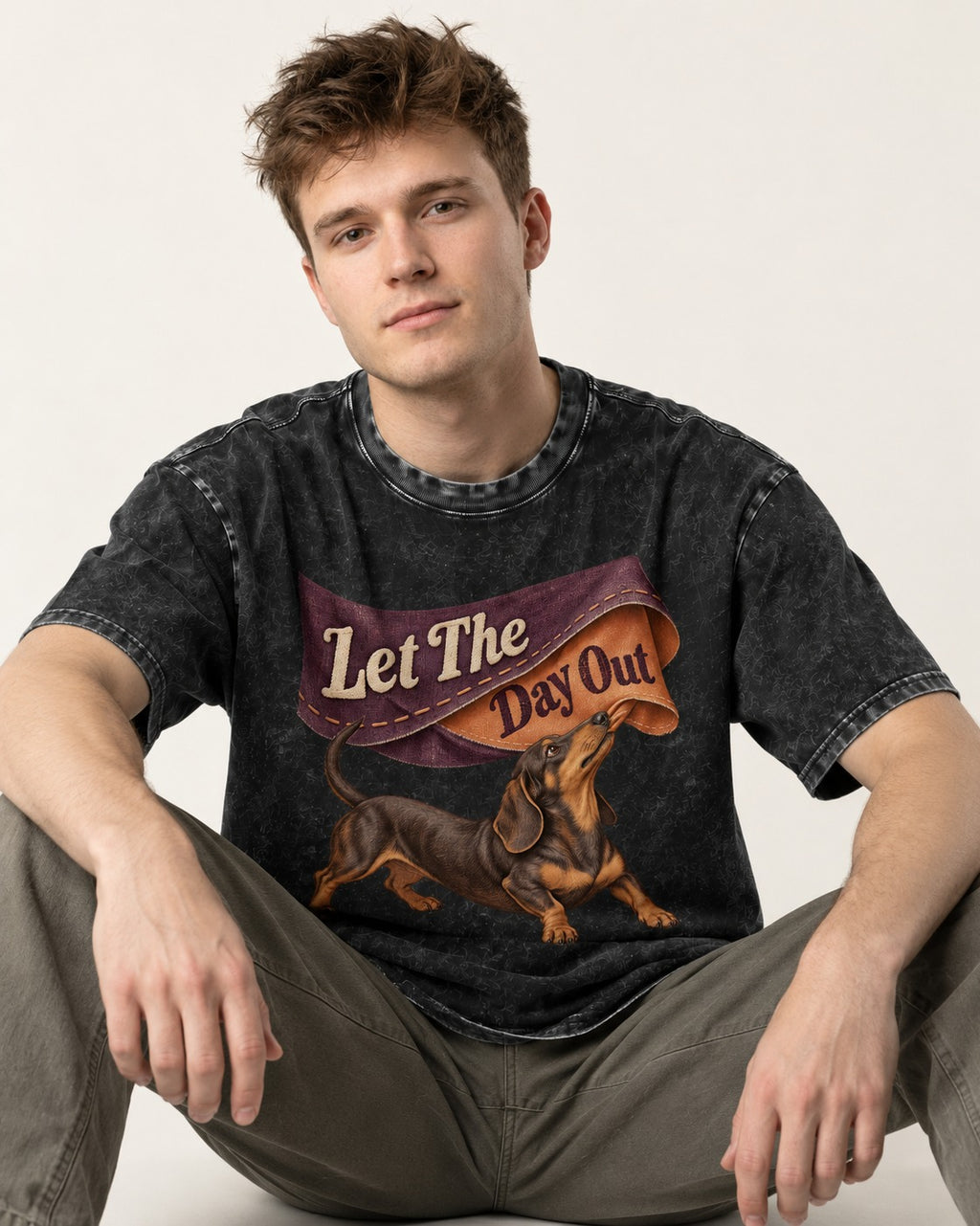 Dachshund Let The Day Out Fabric Banner Graphic Washed Tee in Black, worn by a seated model