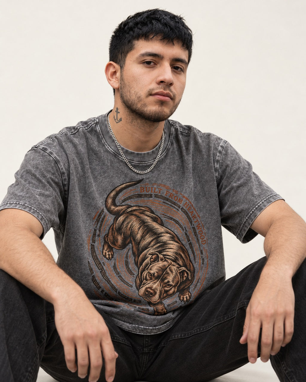 Pitbull Built From Heartwood Washed Tee in Gray, worn by a seated model