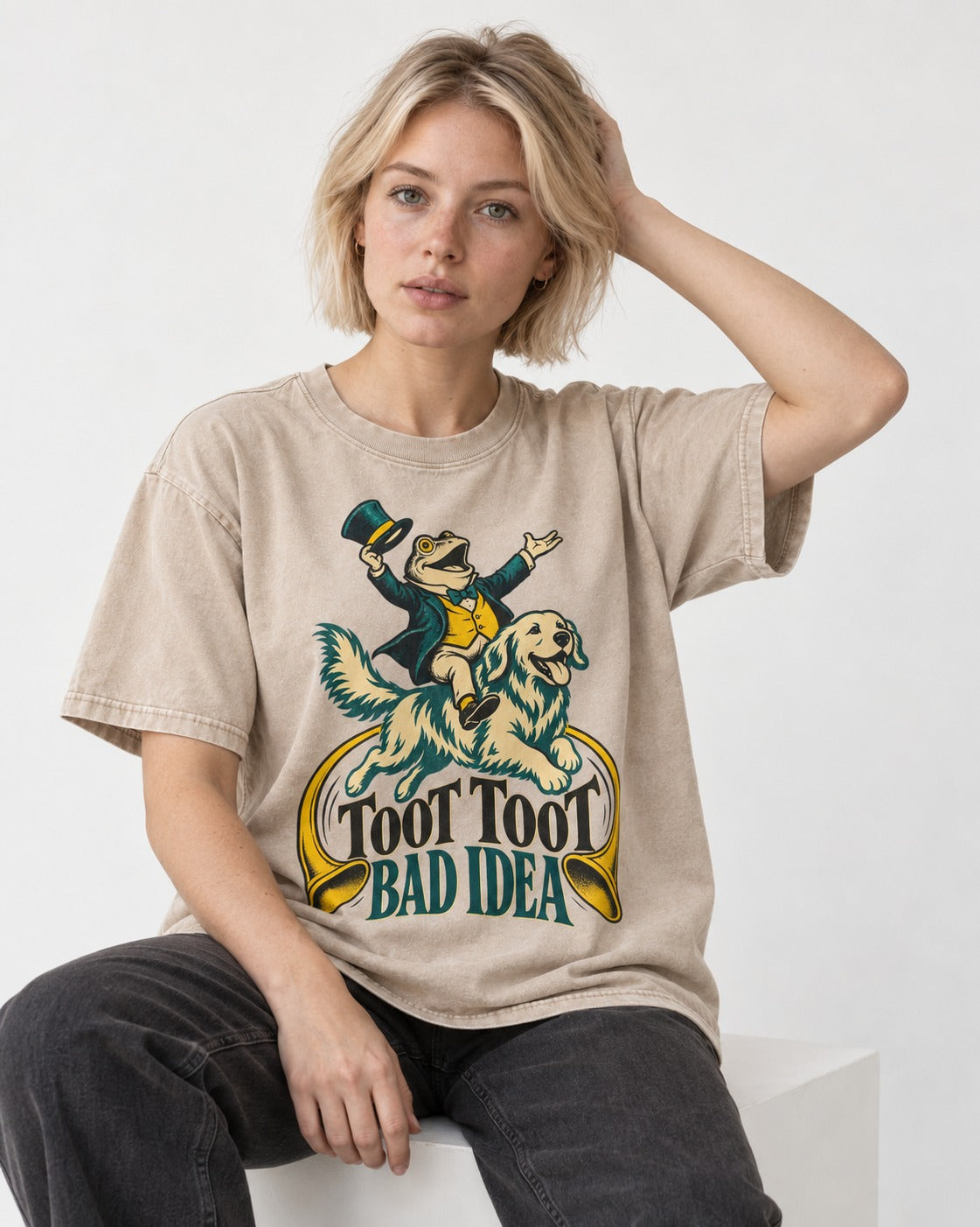 Golden Retriever Toot Toot Bad Idea Washed Tee in Apricot, worn by a seated model