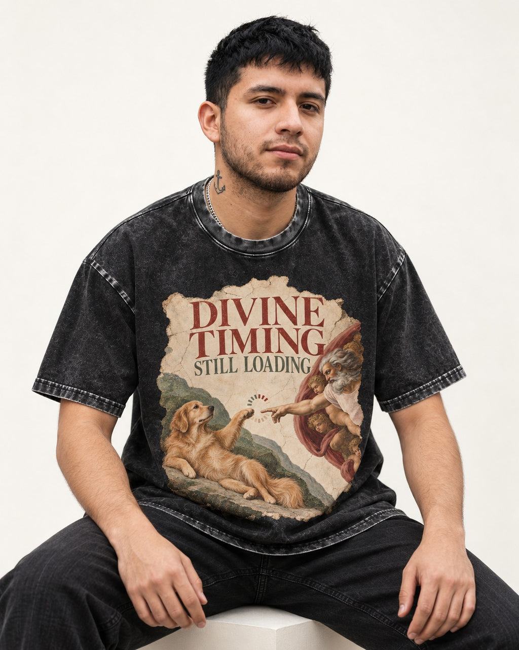 Divine Timing Still Loading Creation Scene Golden Retriever Graphic Washed Tee in Black, worn by a seated model