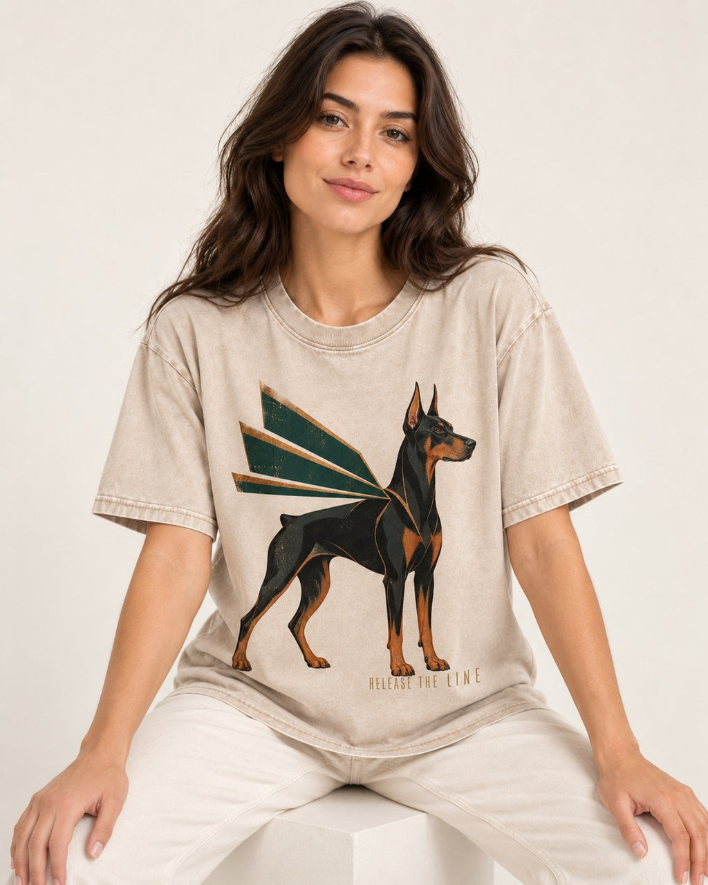 Release the Doberman Line Washed Tee in Apricot, worn by a seated model