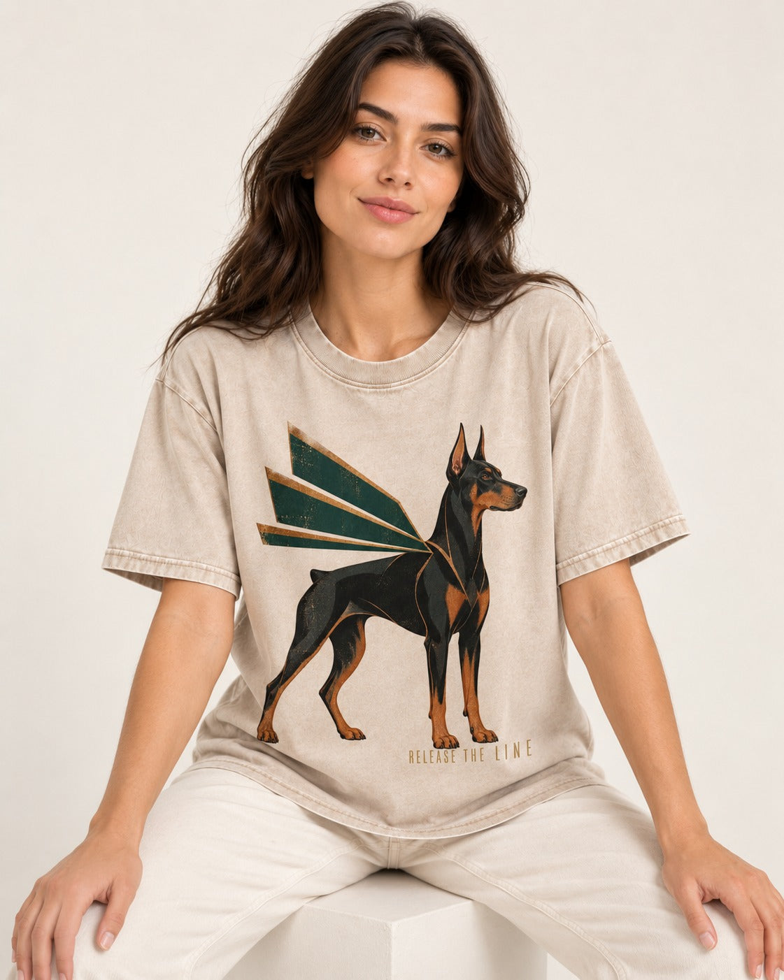 Release the Doberman Line Washed Tee in Apricot, worn by a seated model