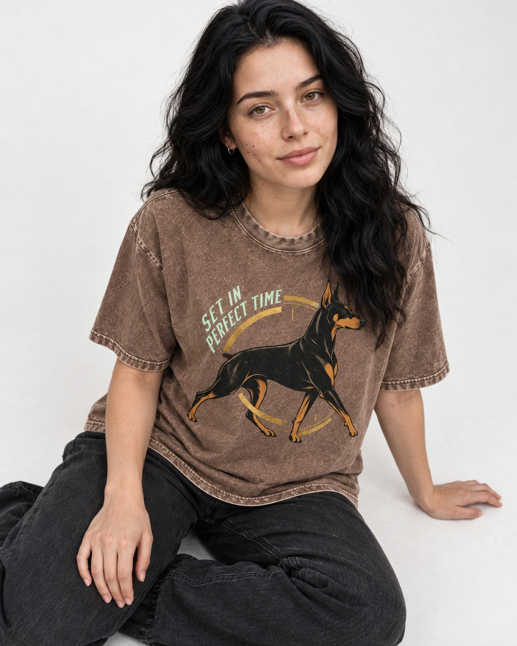 Doberman Set in Perfect Time Clock Stride Graphic Washed Tee in Coffee, worn by a seated model