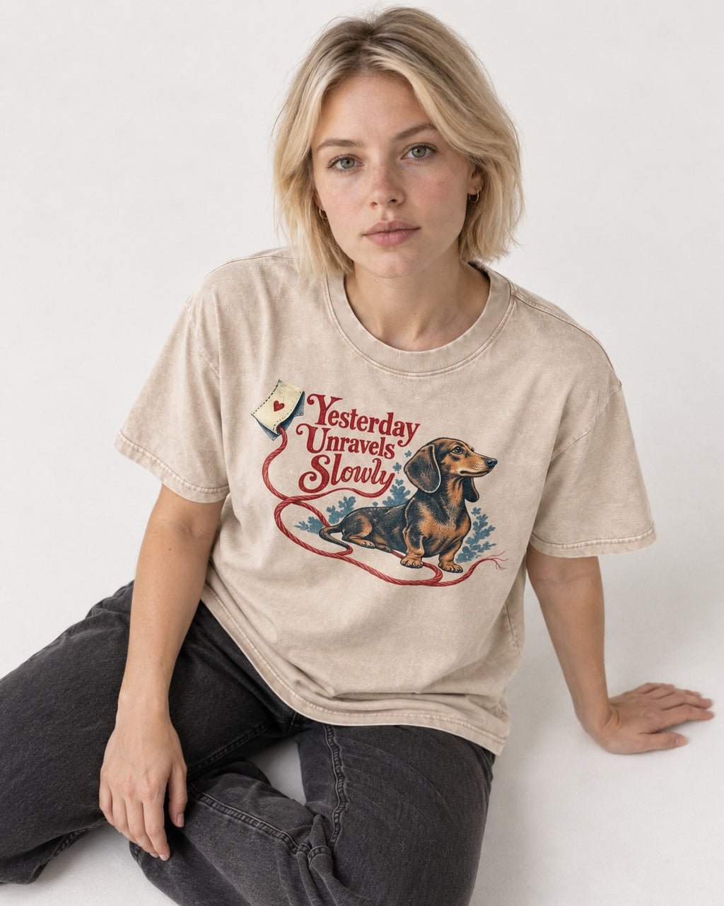 Yesterday Unravels Slowly with Dachshund Washed Tee in Apricot, worn by a seated model