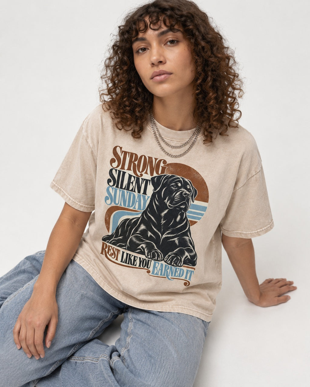 Strong Silent Sunday Rottweiler Washed Tee in Apricot, worn by a seated model