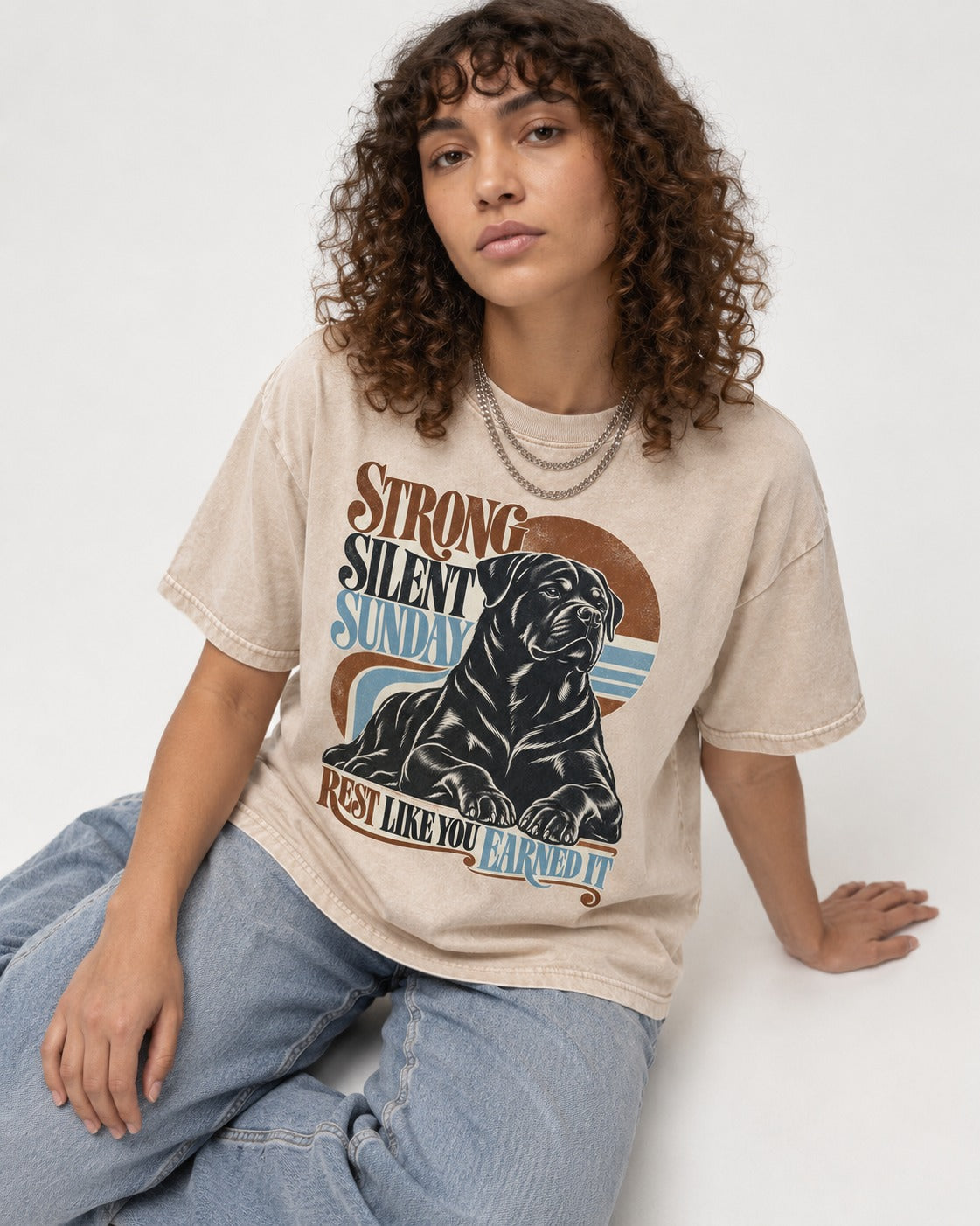 Strong Silent Sunday Rottweiler Washed Tee in Apricot, worn by a seated model