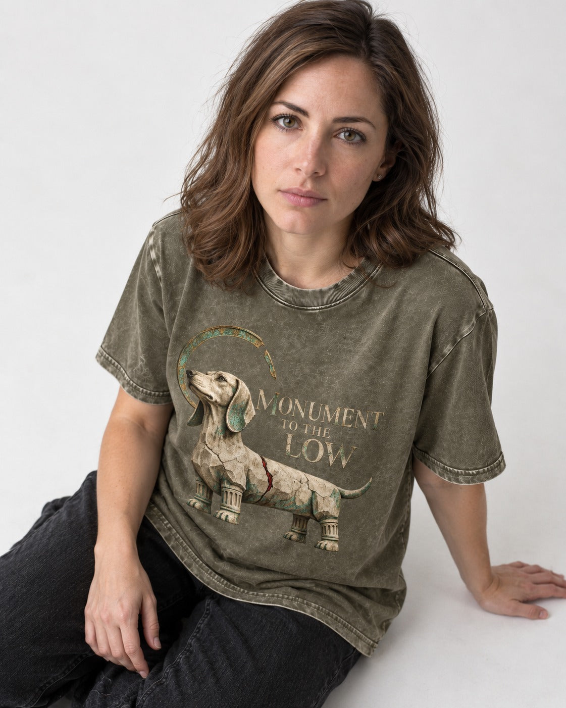 Dachshund Monument to the Low Stone Statue Graphic Washed Tee in Army Green, worn by a seated model