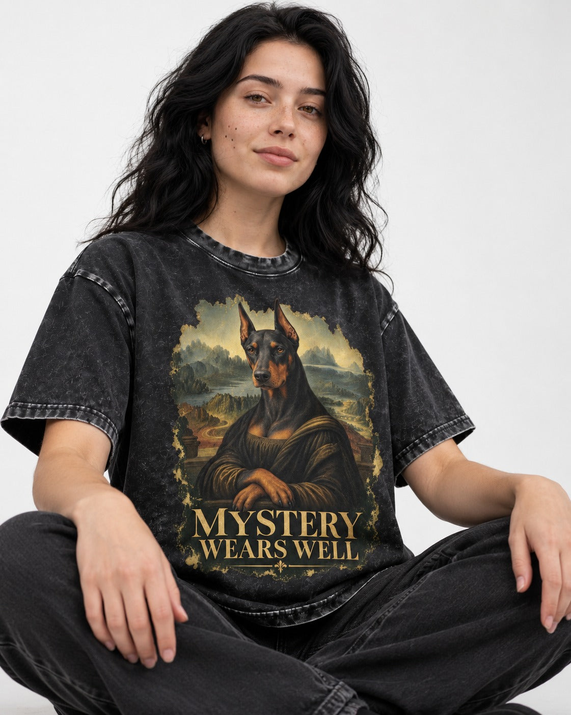 Doberman Mystery Wears Well Renaissance Portrait Graphic Washed Tee in Black, worn by a seated model