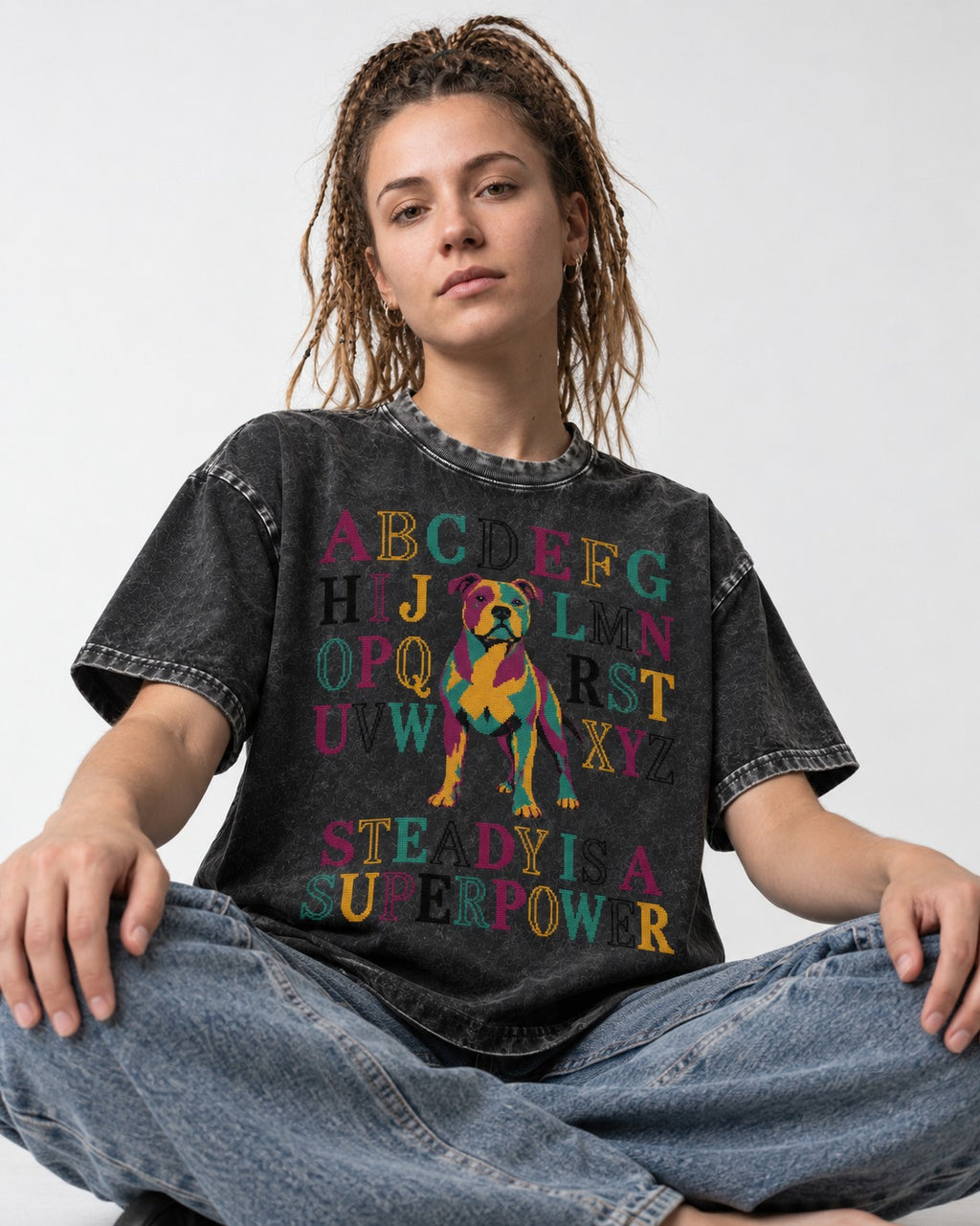 Pitbull Steady Is a Superpower Alphabet Graphic Washed Tee in Black, worn by a seated model