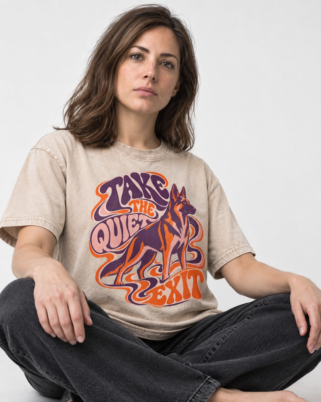 Take The Quiet Exit Psychedelic German Shepherd Dog Graphic Washed Tee in Apricot, worn by a seated model