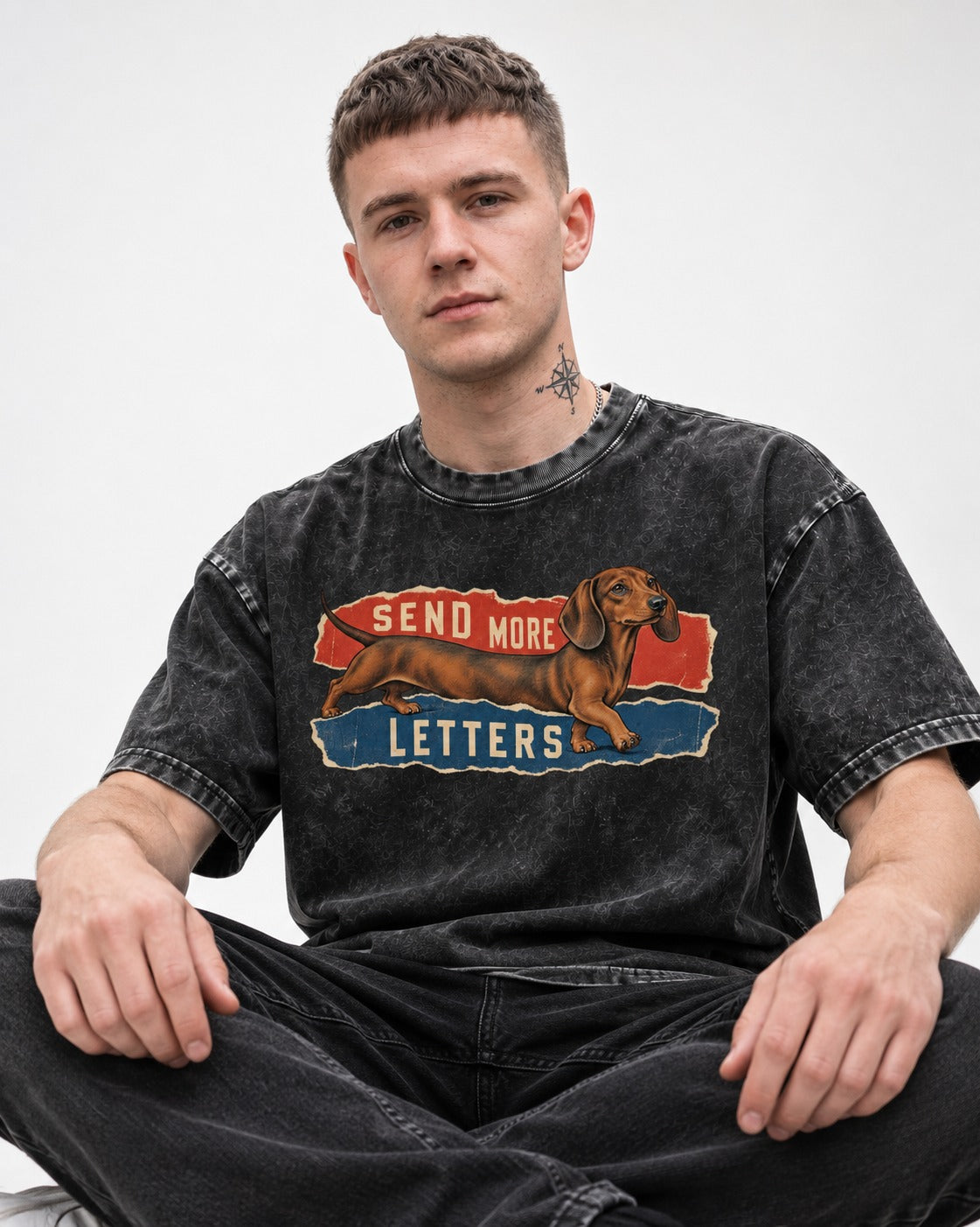 Dachshund Send More Letters Torn Paper Graphic Washed Tee in Black, worn by a seated model
