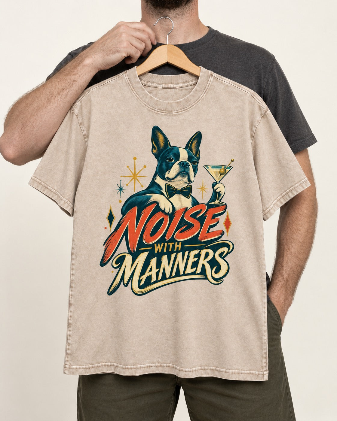 Boston Terrier Noise With Manners Cocktail Graphic Washed Tee in Apricot, held up on a hanger