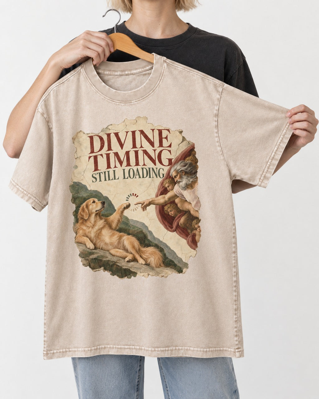 Divine Timing Still Loading Creation Scene Golden Retriever Graphic Washed Tee in Apricot, held up on a hanger