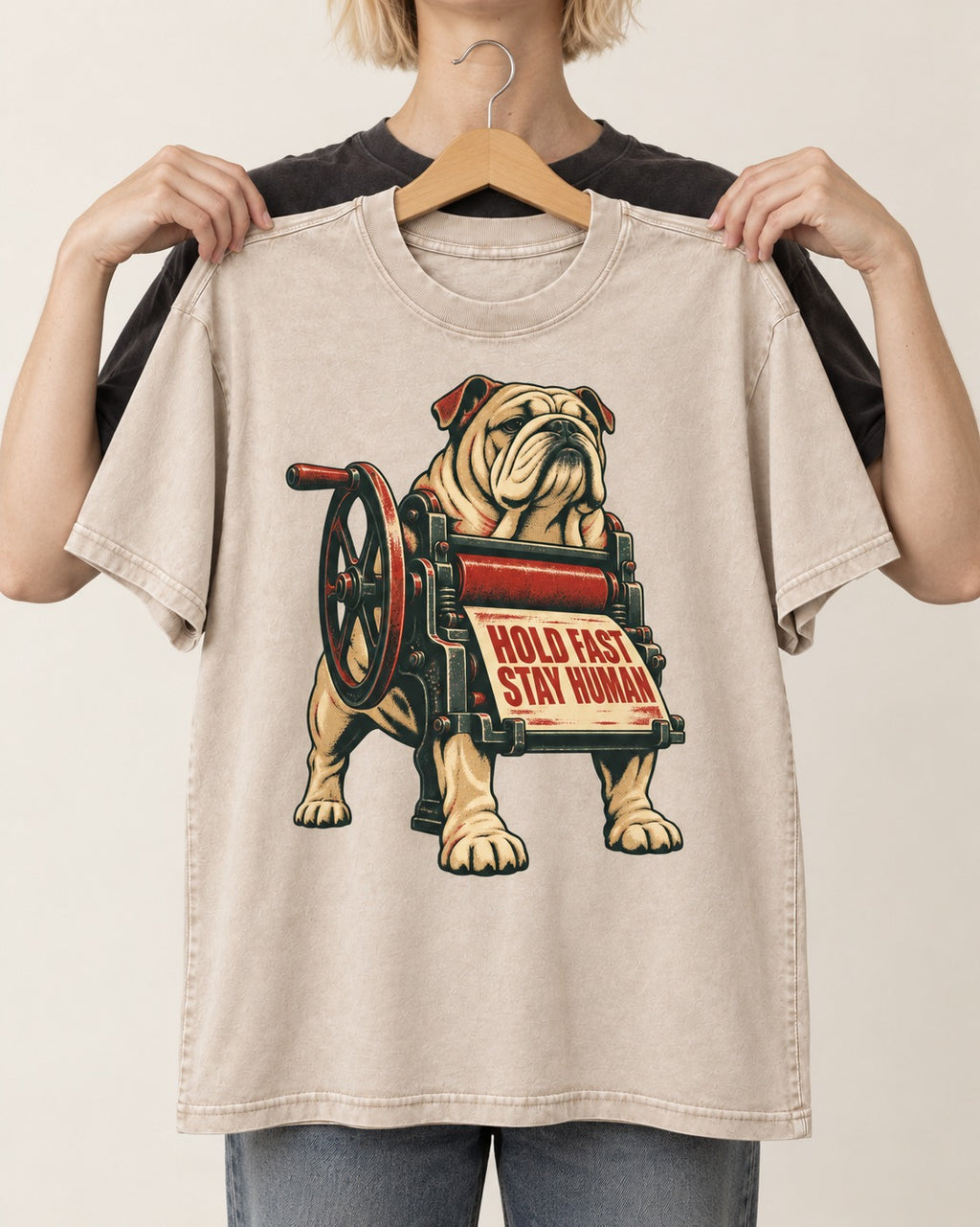 Hold Fast Stay Human English Bulldog Washed Tee in Apricot, held up on a hanger