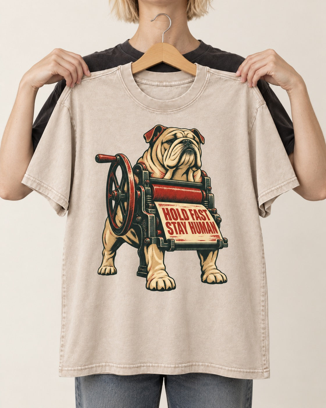 Hold Fast Stay Human English Bulldog Washed Tee in Apricot, held up on a hanger