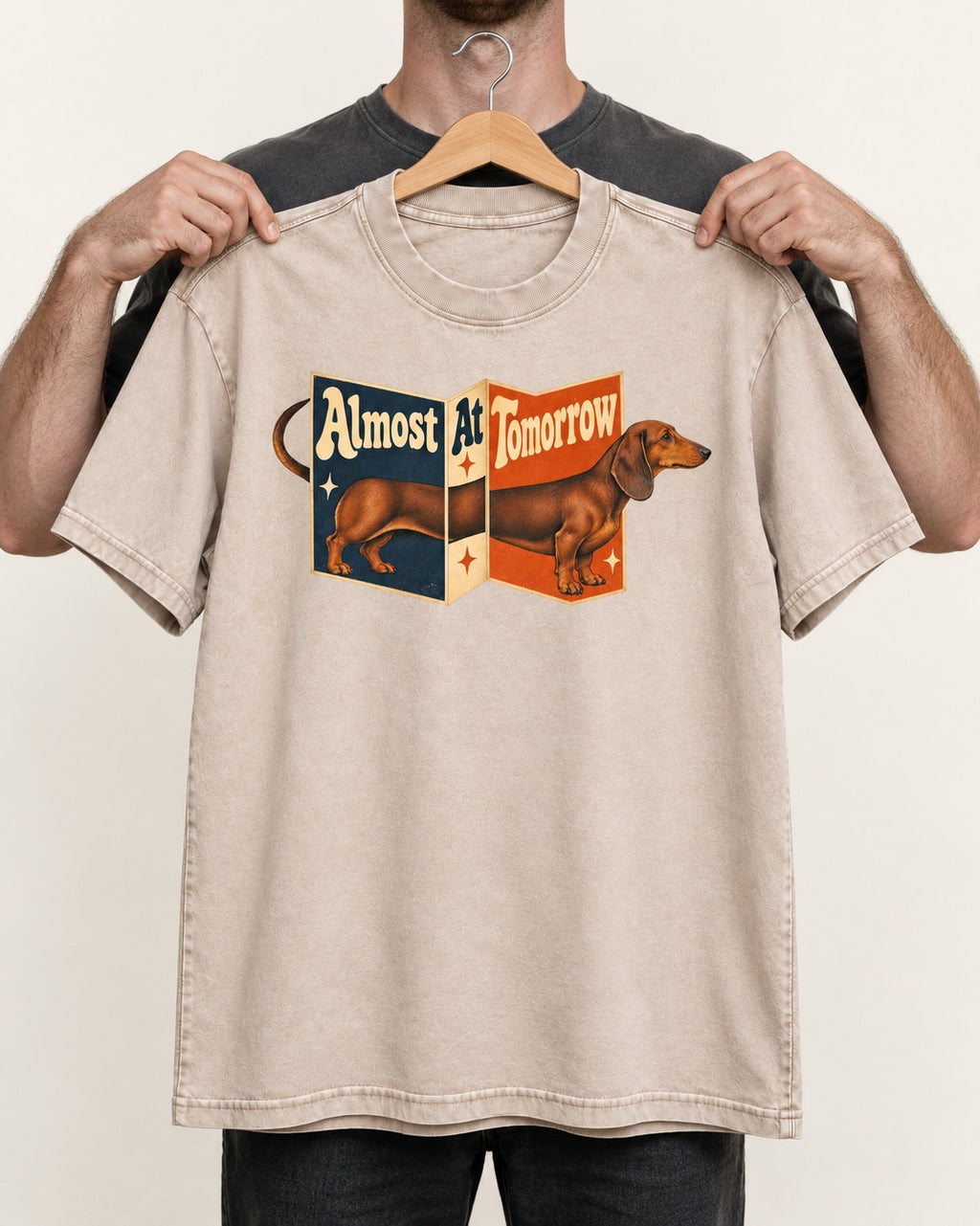 Dachshund Almost At Tomorrow Folding Screen Graphic Washed Tee in Apricot, held up on a hanger