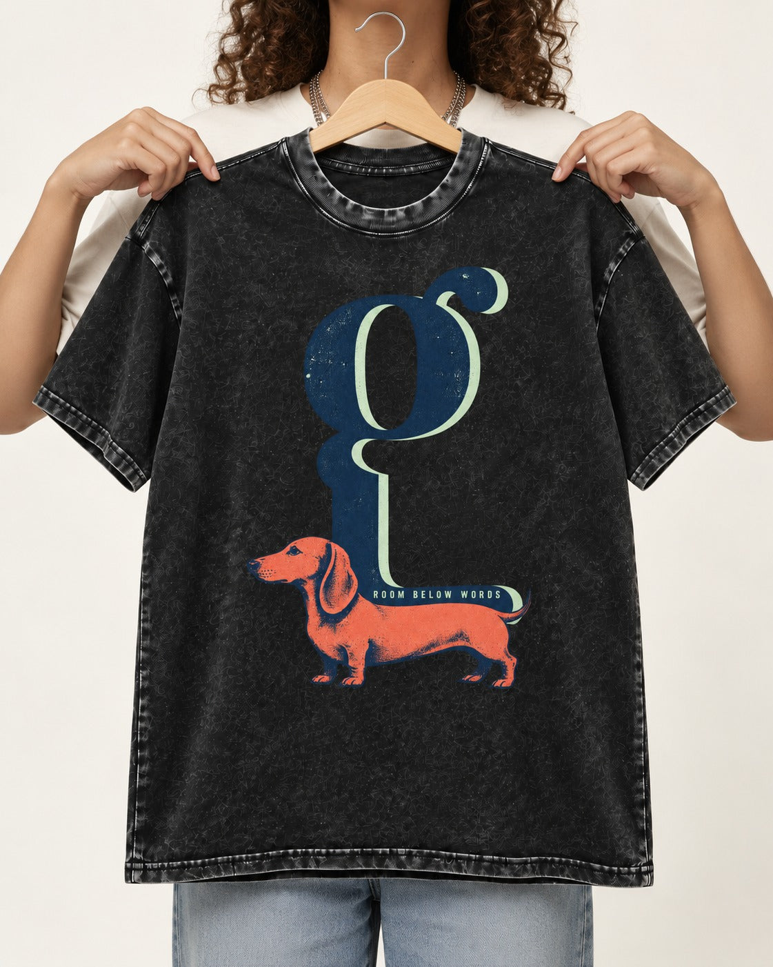 Dachshund Room Below Words Lowercase G Graphic Washed Tee in Black, held up on a hanger