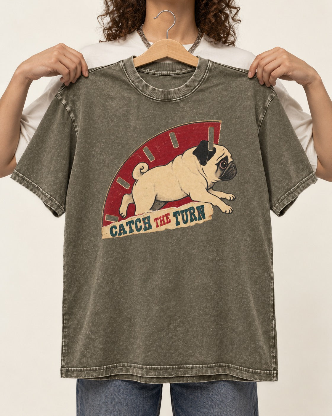 Pug Catch the Turn Track Graphic Washed Tee in Army Green, held up on a hanger