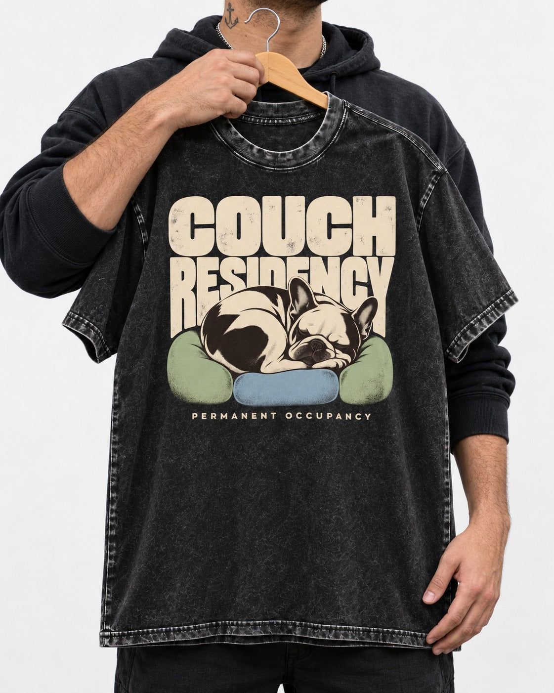Frenchie Couch Residency Permanent Occupancy Cushion Graphic Washed Tee in Black, held up on a hanger