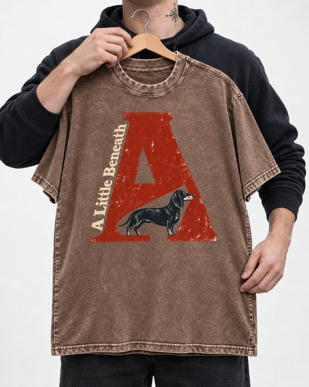 Dachshund A Little Beneath Monumental Letter Graphic Washed Tee in Coffee, held up on a hanger