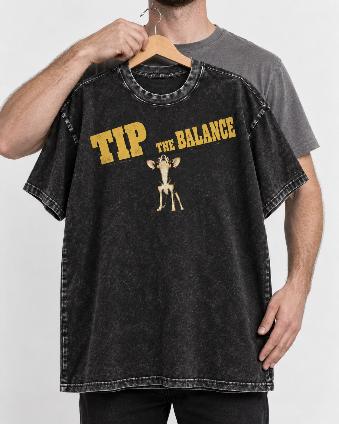 Chihuahua Tip the Balance Beam Graphic Washed Tee in Black, held up on a hanger