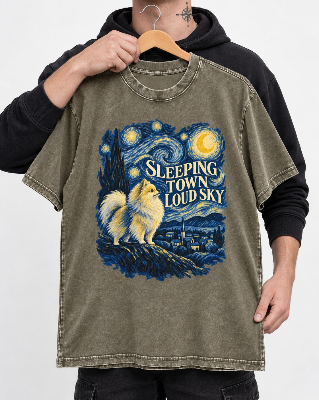 Pomeranian Sleeping Town Loud Sky Starry Night Graphic Washed Tee in Army Green, held up on a hanger