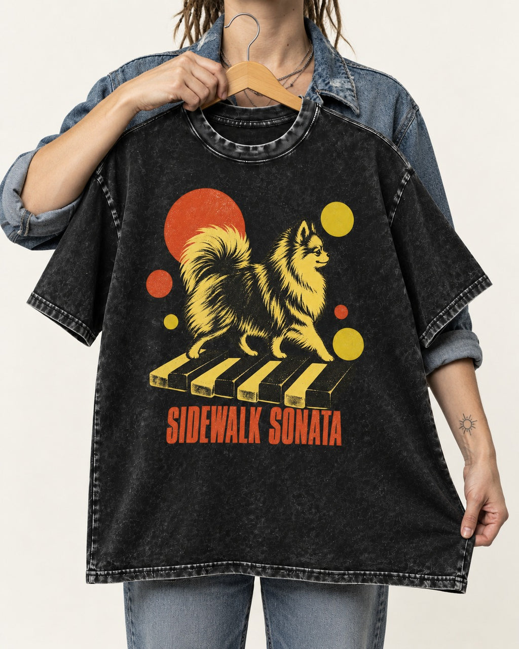 Pomeranian Sidewalk Sonata Piano Graphic Washed Tee in Black, held up on a hanger