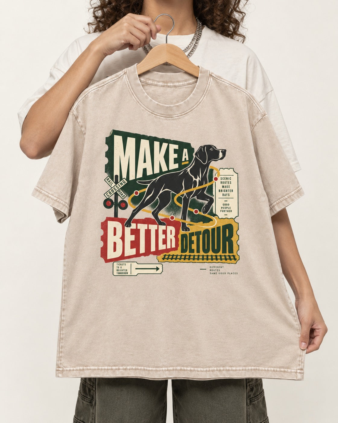 German Shorthaired Pointer Make a Better Detour Railroad Graphic Washed Tee in Apricot, held up on a hanger