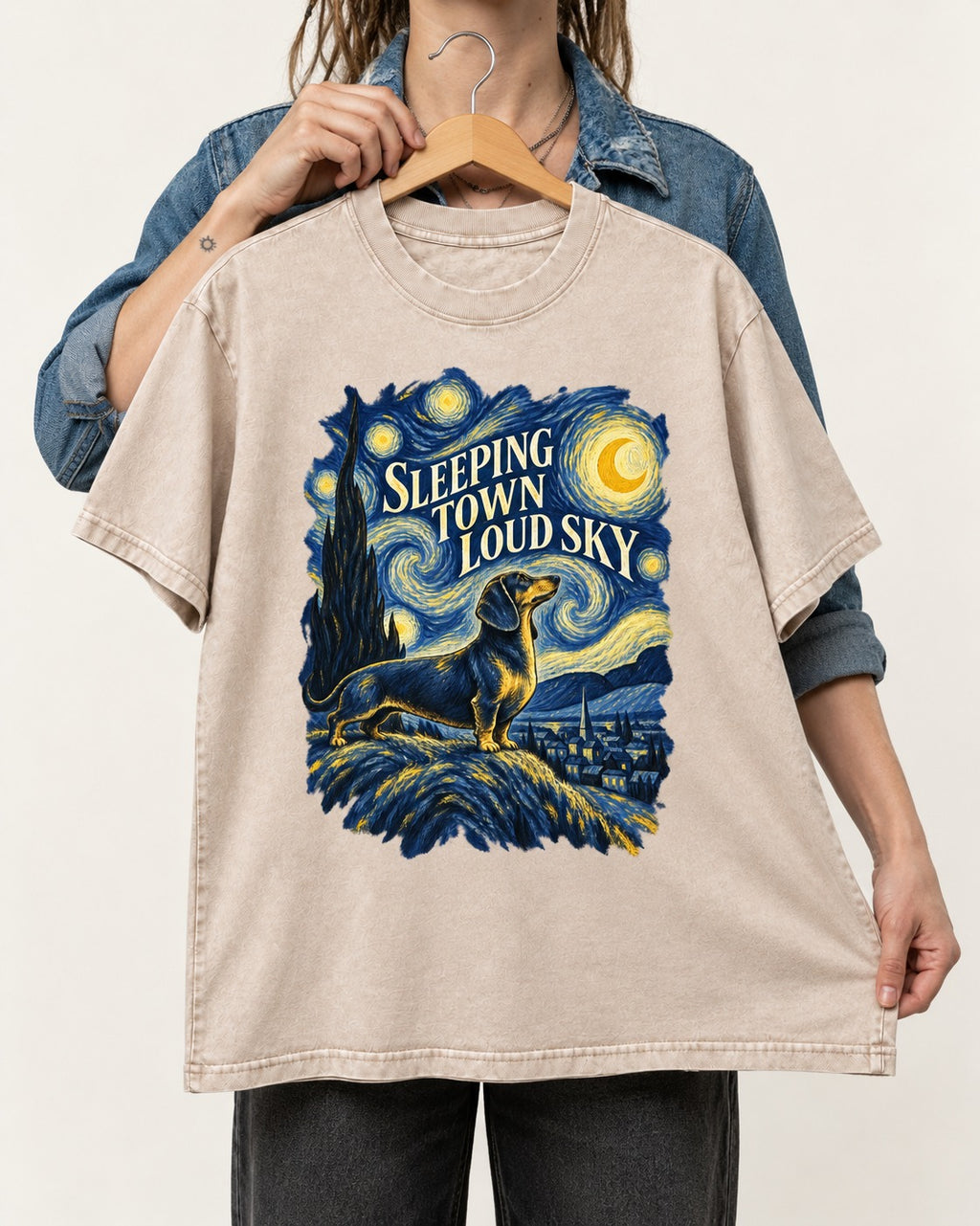 Dachshund Sleeping Town Loud Sky Starry Night Graphic Washed Tee in Apricot, held up on a hanger