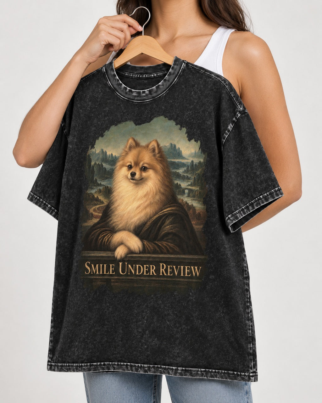 Pomeranian Smile Under Review Renaissance Portrait Graphic Washed Tee in Black, held up on a hanger