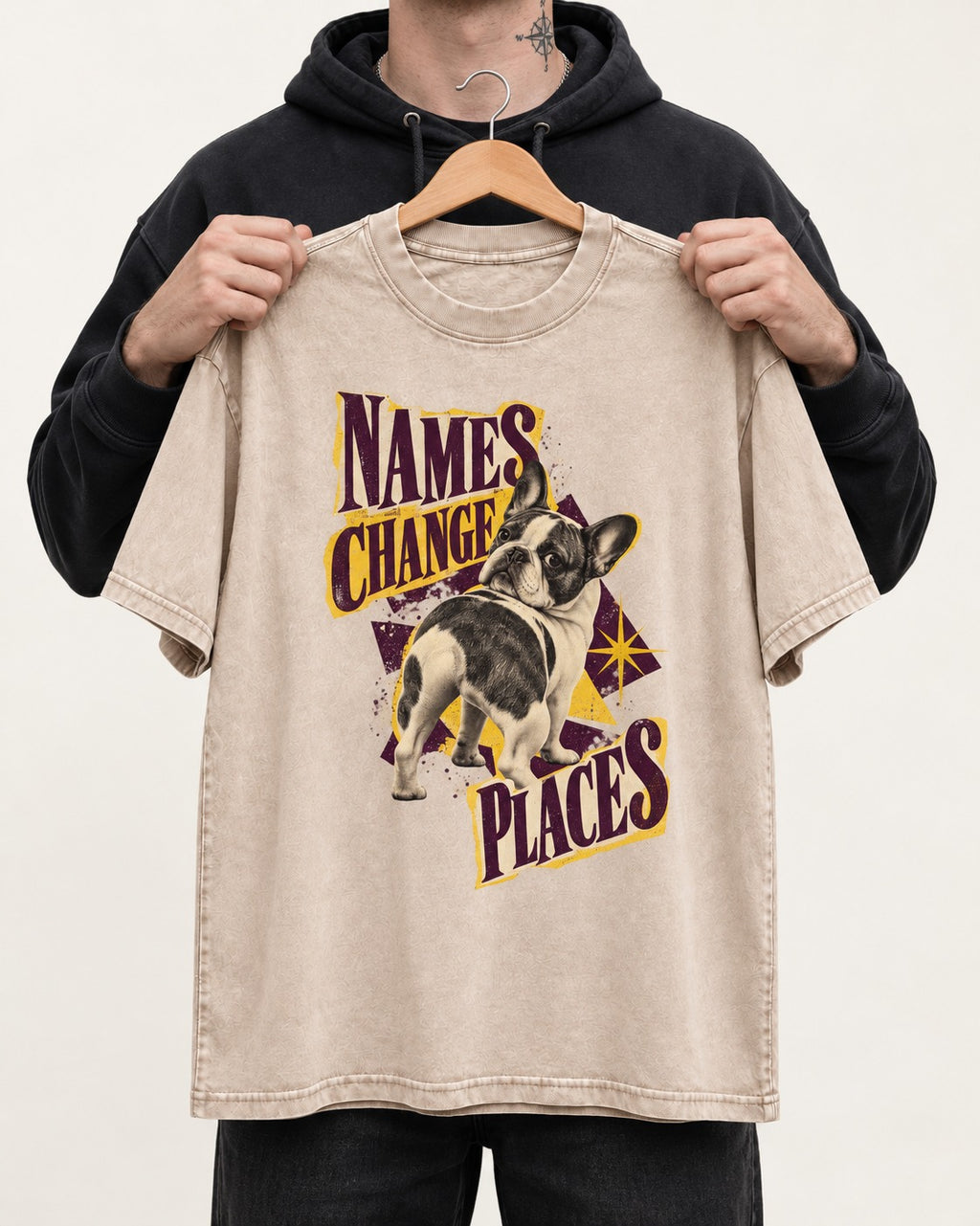 Frenchie Names Change Places Purple Poster Graphic Washed Tee in Apricot, held up on a hanger