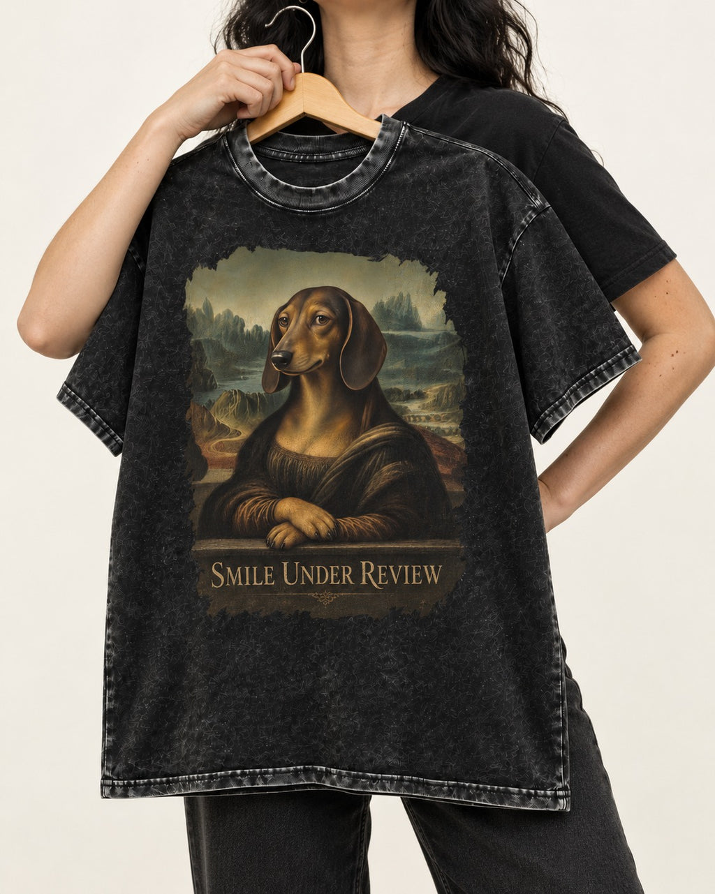 Dachshund Smile Under Review Mona Lisa Graphic Washed Tee in Black, held up on a hanger