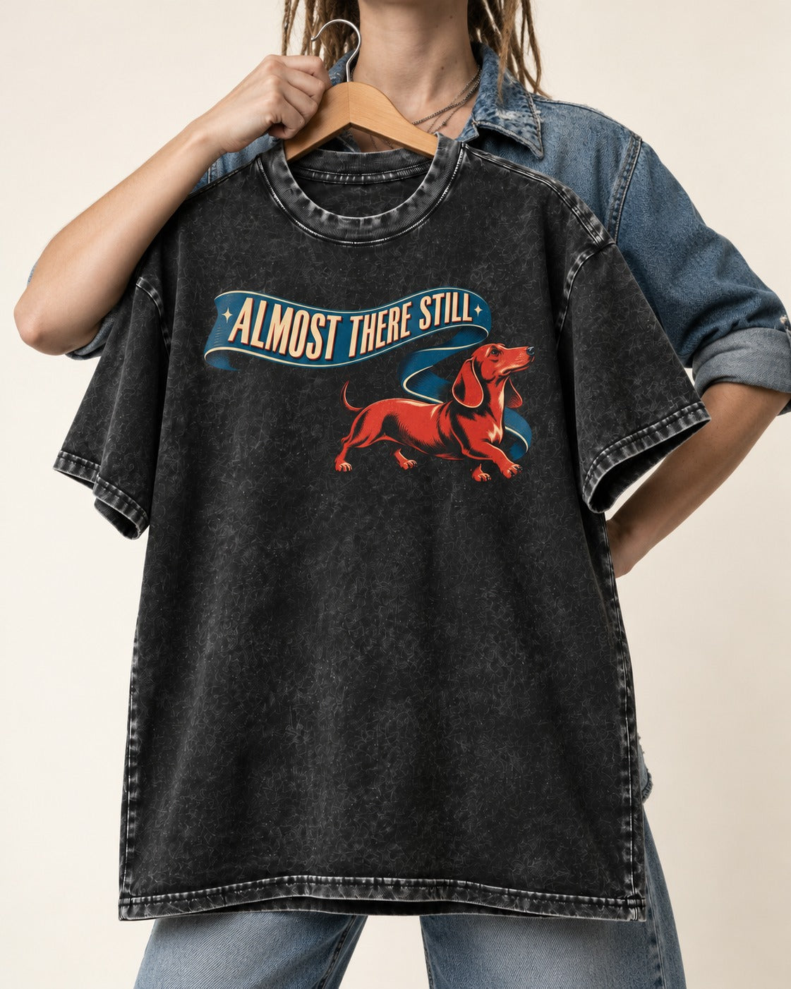 Dachshund Almost There Still Ribbon Graphic Washed Tee in Black, held up on a hanger