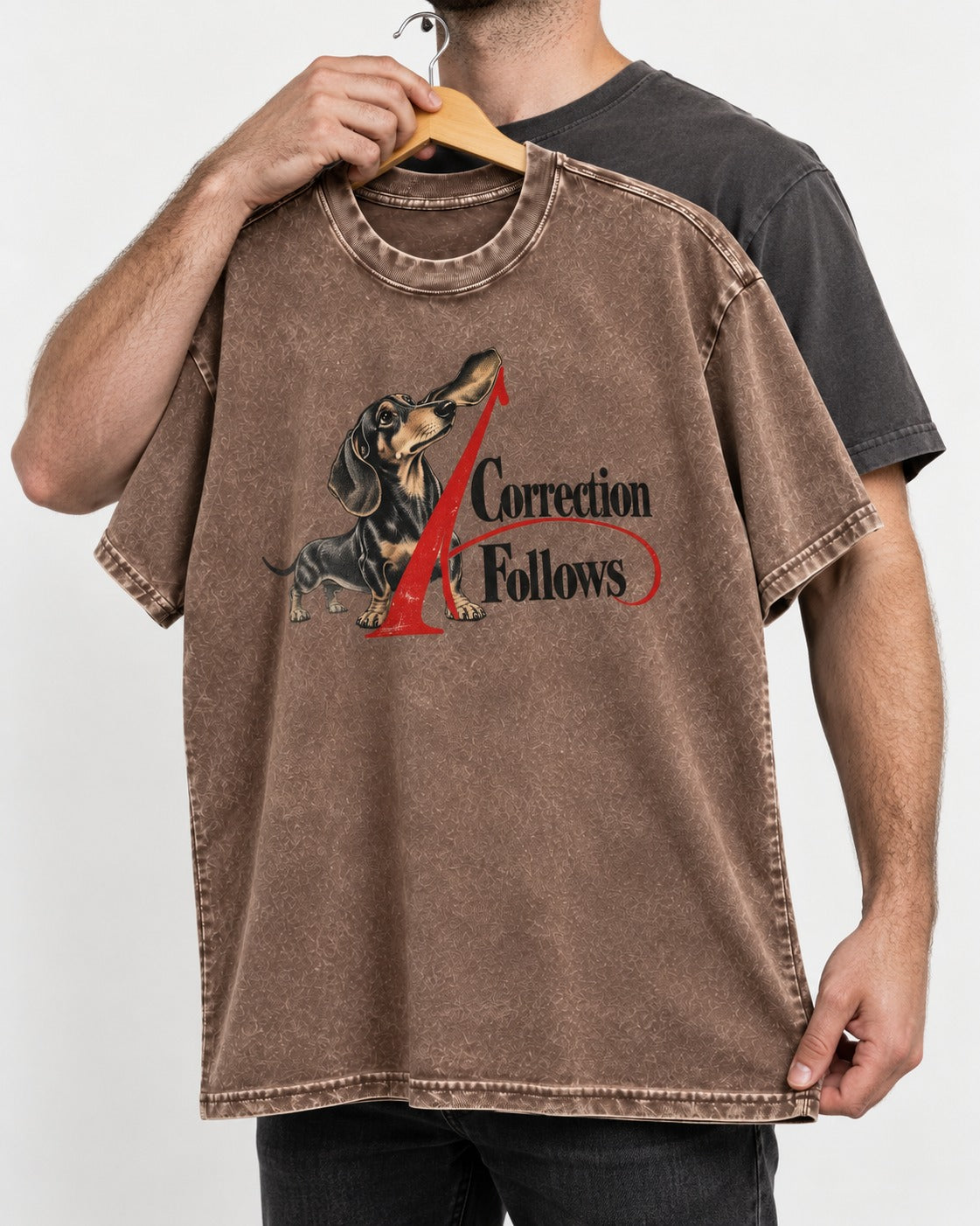 A Dachshund Correction Follows Washed Tee in Coffee, held up on a hanger