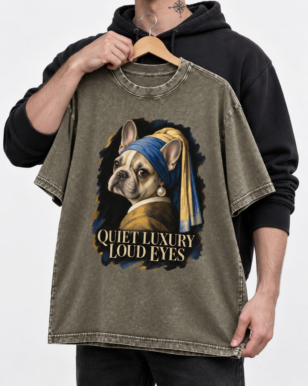 Frenchie Quiet Luxury Loud Eyes Pearl Portrait Graphic Washed Tee in Army Green, held up on a hanger